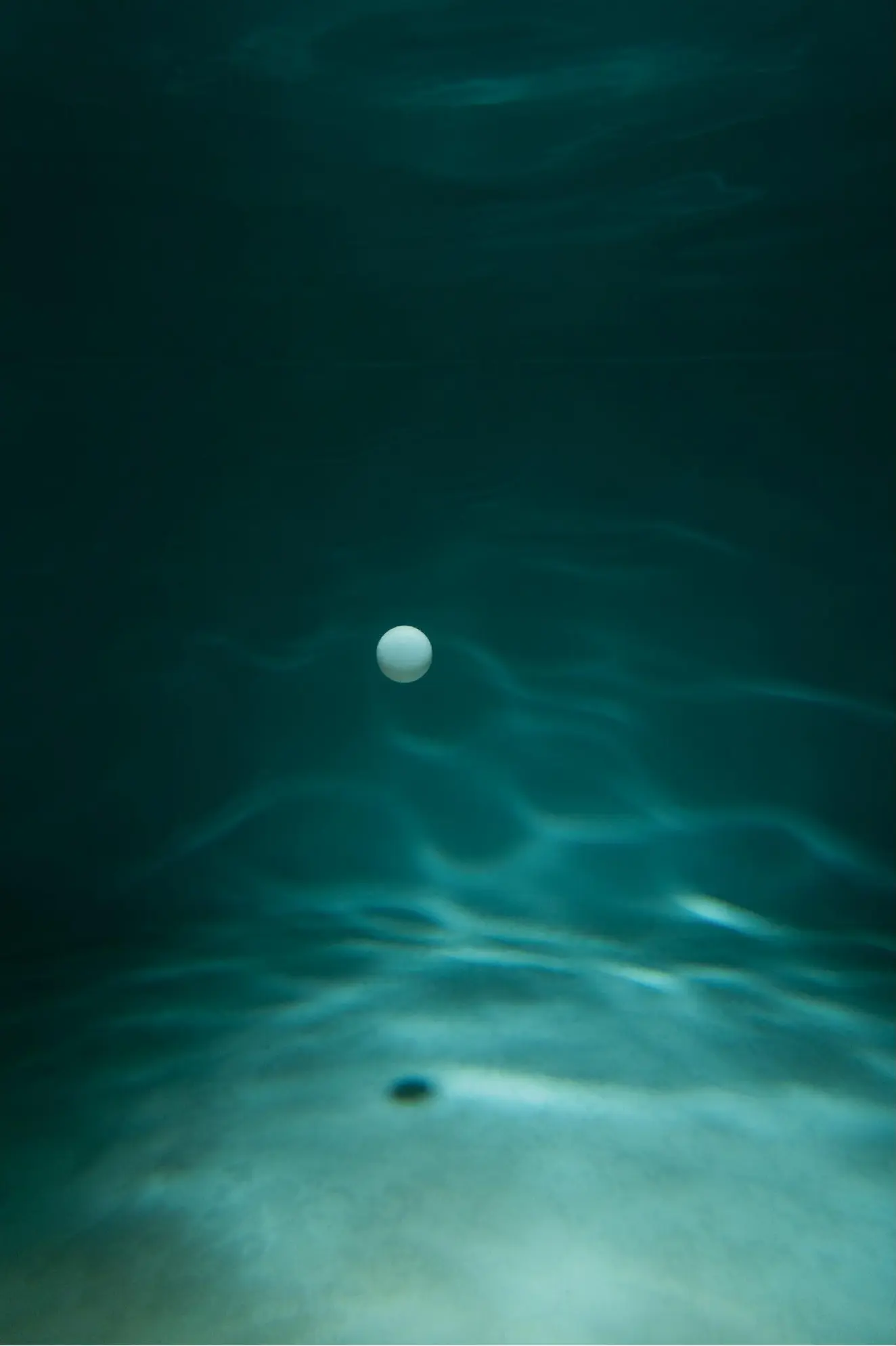 A pale sphere suspended above the floor of an underwater set
