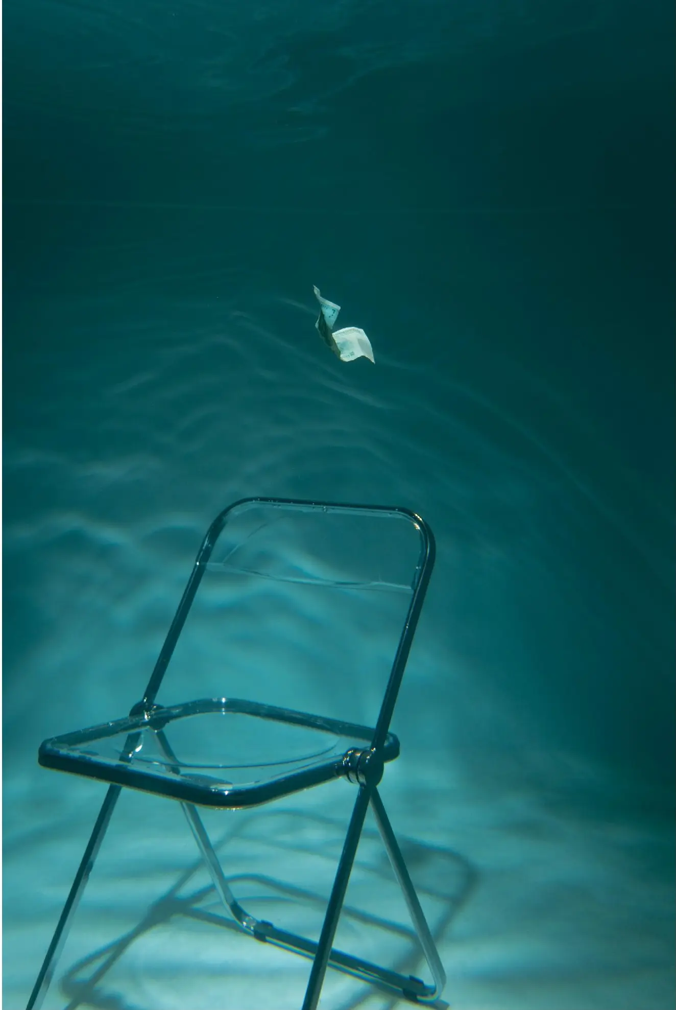 An empty transparent chair beneath a small floating form