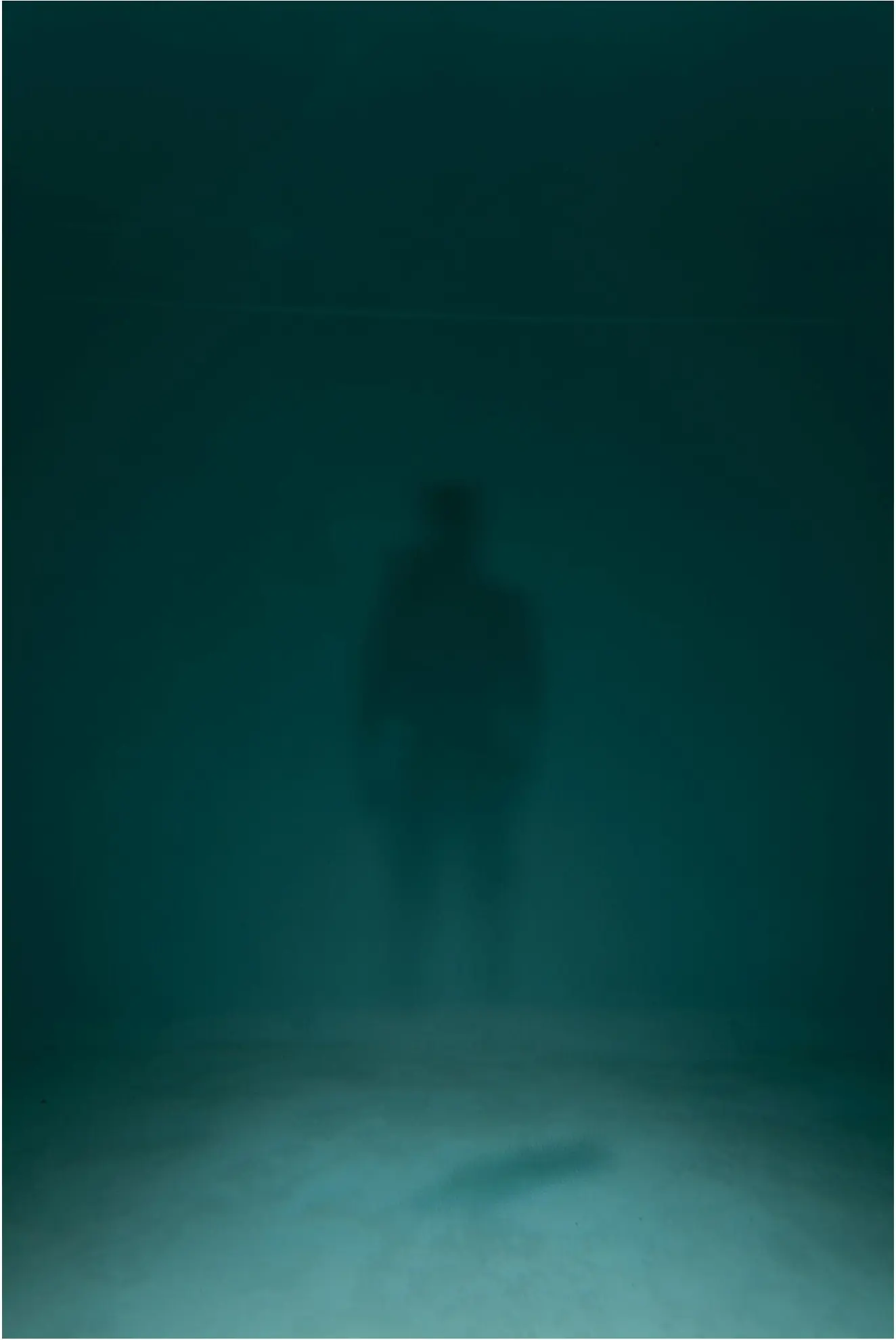 A distant human silhouette blurred behind deep green water